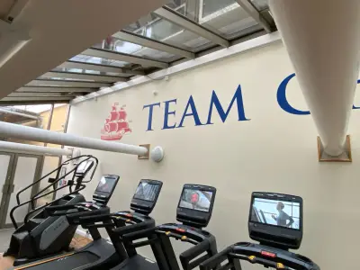 Gym wall with red sailing-ship logo and blue Team lettering above treadmills