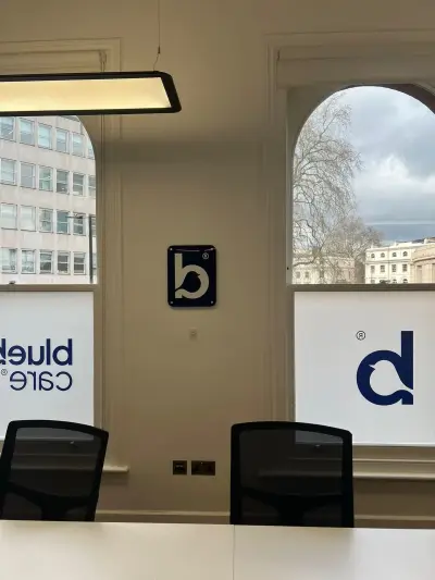 Bluebird Care logo window frosting on arched office windows, with wall-mounted bird logo plaque