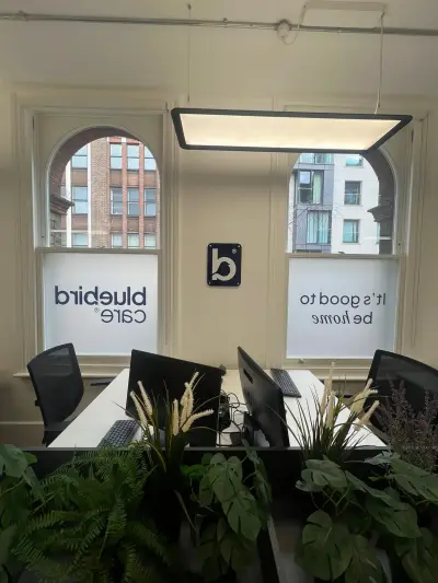 Bluebird Care frosted window graphics with logo and slogan across arched office windows