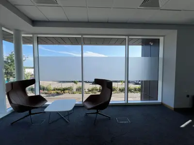 Corporate office lounge with frosted privacy band applied across full-height glazing