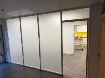 Office partition with frosted glass panels beside a doorway to a kitchen