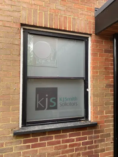 KJ Smith Solicitors window graphic on frosted glass of a red-brick building