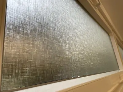 Linen-texture frosted window film seen at an angle on a cream-framed window