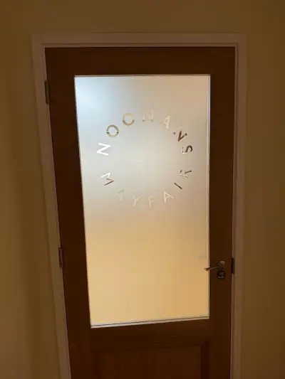 Noonans Mayfair frosted graphic with circular cut-out lettering on a wooden glazed door