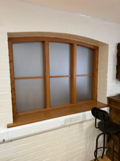 Arched wooden-framed windows fitted with grey frosted privacy film