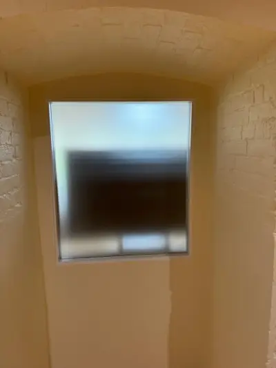 Arched recessed window with plain frosted privacy film in a painted-brick wall
