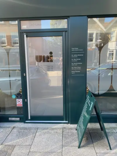 Umi Clinic entrance door with frosted graphic showing logo, opening hours and clinician names