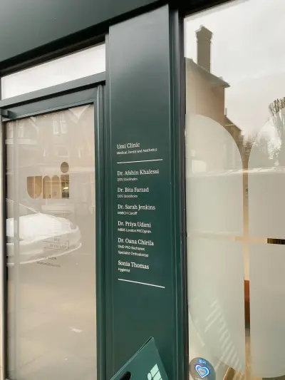 Green shopfront pillar with white vinyl lettering listing Umi Clinic medical and dental practitioners