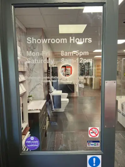 Glass door with white vinyl Showroom Hours lettering on a bathroom showroom entrance