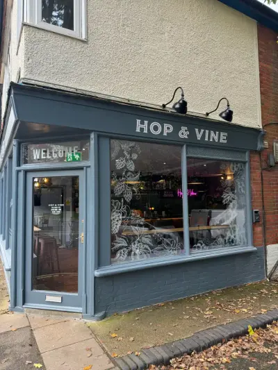 Grey corner shopfront with Hop & Vine fascia sign and etched hop-vine window graphics