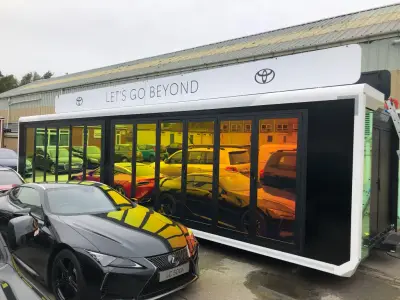 Toyota mobile showroom trailer with Let's Go Beyond graphics; black striped Lexus LC500h alongside