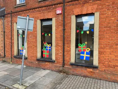 Red-brick shopfront windows with festive gift-box and fairy-light window graphics