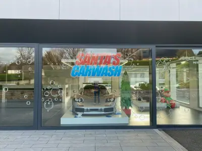 Santa's Carwash festive window graphics on McLaren showroom with silver supercar and elf