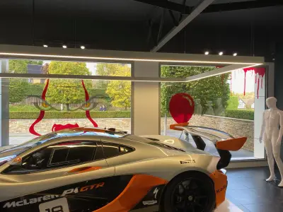 McLaren P1 GTR racing car in showroom with red drip and clown-face Halloween window graphics