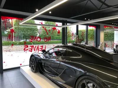 Black McLaren P1 in showroom with red No One Leaves blood-splatter Halloween window graphics
