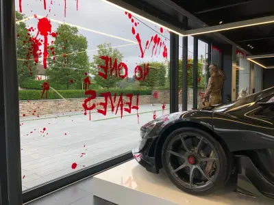 Black McLaren P1 by showroom window with No One Leaves blood-splatter Halloween graphics