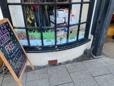 Bow shop window with painted snowy village-scene graphics behind Saucony trainer boxes