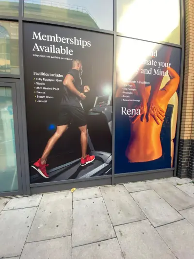 Installer on a scaffold tower fitting an Athlete Movement quote wall sign inside a gym
