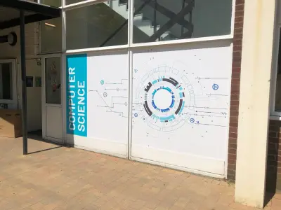 Computer Science window graphic with teal circuit motif on a school building frontage
