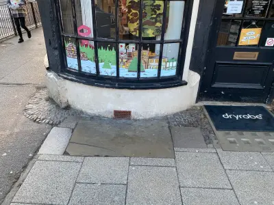 Corner shop curved bay window with painted festive snowy-village graphics and dryrobe doormat