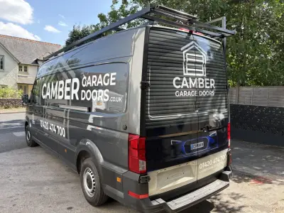 Grey van fully wrapped for Camber Garage Doors with white house-shaped logo and phone number