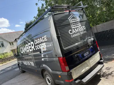 Grey wrapped van with Camber Garage Doors branding and phone number, rear three-quarter view